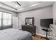 A main bedroom with a tray ceiling, fan, dresser with mirror, TV on a stand, and light gray walls at 308 Clearwater Ln, Poinciana, FL 34759