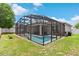 Expansive backyard oasis with a sparkling pool, screened enclosure, and lush green surroundings at 308 Clearwater Ln, Poinciana, FL 34759