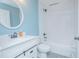 Bright bathroom with white vanity, round mirror, and tiled shower-tub combo, showcasing modern finishes and a clean design at 4911 Ne 7Th St, Ocala, FL 34470