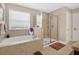 Bright bathroom with a soaking tub, glass enclosed shower, and neutral tile at 561 Gunston Ct, Davenport, FL 33837