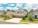 Two-story home with a three-car garage, lush landscaping, and a sunny blue sky at 561 Gunston Ct, Davenport, FL 33837