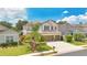 Two-story home with a three-car garage, lush landscaping, and a sunny blue sky at 561 Gunston Ct, Davenport, FL 33837