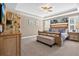Spacious main bedroom featuring tray ceiling, ceiling fan, unique book wall, and seating bench at 561 Gunston Ct, Davenport, FL 33837