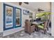 Inviting outdoor dining area with a ceiling fan, TV, grill, and blue French doors leading to the pool at 561 Gunston Ct, Davenport, FL 33837