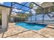 Screened-in pool with a waterfall feature and tile accents, surrounded by a paved patio at 561 Gunston Ct, Davenport, FL 33837