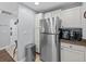 Well-lit kitchen featuring stainless steel refrigerator, white cabinetry, and tile backsplash at 7615 Heritage Crossing Way # 201, Reunion, FL 34747