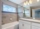 Well-lit bathroom with a tub, tile surround, single sink, and view from the window at 850 Pebble Beach Dr, Davenport, FL 33896