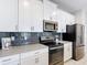 Modern kitchen featuring white cabinets, stainless steel appliances, and dark backsplash tiles at 850 Pebble Beach Dr, Davenport, FL 33896