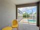 A cozy, screened-in patio features a yellow metal seating set and view of a screened-in pool and green backyard at 850 Pebble Beach Dr, Davenport, FL 33896