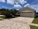 Charming home with a brick driveway, lush landscaping, and a two-car garage on a beautiful day at 9003 Pecky Cypress Way, Orlando, FL 32836