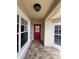 Welcoming front porch with beautiful tile flooring, a bright red door, and sidelight windows at 9003 Pecky Cypress Way, Orlando, FL 32836