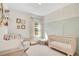 Serene Bedroom with a crib, comfortable seating, and decorative wallpaper, creating a cozy and inviting space at 913 Sabal Breeze Ln, Apopka, FL 32703