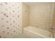 Floral wallpapered bathroom featuring a tiled bathtub at 9206 Everwood St, Orlando, FL 32825