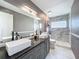 Bright bathroom features double vessel sinks, black fixtures, stylish vanity, and marble tiled shower at 1044 Dees Dr, Oviedo, FL 32765