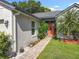 Close-up of the home's entrance, showcasing the orange front door, stone pathway, and mature landscaping at 1044 Dees Dr, Oviedo, FL 32765