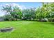 Large backyard featuring green grass, a fire pit, and a wood fence at 1113 Canopy Oaks Dr, Minneola, FL 34715