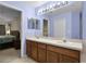 Bathroom featuring double sinks, large mirror, and views of the open doorway to the bedroom at 1113 Canopy Oaks Dr, Minneola, FL 34715
