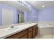 Bathroom featuring double sinks, large mirror, and tub with tile surround at 1113 Canopy Oaks Dr, Minneola, FL 34715