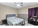 Bedroom with ceiling fan, nautical themed quilt, gray headboard, and a window with purple curtains at 1113 Canopy Oaks Dr, Minneola, FL 34715