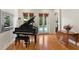 Bright living room features a grand piano, hardwood floors, french doors, and backyard pool views at 1394 Grove Ter, Winter Park, FL 32789
