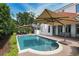 Inviting pool area with brick-paver patio, large umbrella, and beautiful landscaping at 1394 Grove Ter, Winter Park, FL 32789