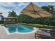 Backyard pool with patio, sun umbrellas, lounge chairs, and privacy landscaping at 1394 Grove Ter, Winter Park, FL 32789