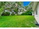 Well-manicured backyard with large mature trees, lush green grass, and water in the distance at 1420 Rock Lake Dr, Orlando, FL 32805