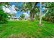 Spacious backyard featuring mature trees, lush green grass, and home with white-framed windows at 1420 Rock Lake Dr, Orlando, FL 32805