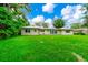Exterior view of the home with a sprawling backyard featuring lush grass and mature trees at 1420 Rock Lake Dr, Orlando, FL 32805