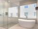 Bright bathroom showcasing a glass-enclosed shower and freestanding soaking tub near a large window at 16210 Ravenna Ct, Montverde, FL 34756