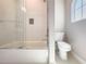 Tiled shower-tub combo features a glass door, niche, and a toilet with arched window nearby at 16210 Ravenna Ct, Montverde, FL 34756