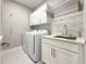 Bright laundry room featuring a sink, ample cabinet space, and modern appliances for convenience at 16210 Ravenna Ct, Montverde, FL 34756