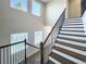 Well-lit staircase with dark wood steps and black iron railing showcases the bright and airy atmosphere at 16210 Ravenna Ct, Montverde, FL 34756