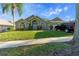 Inviting home exterior featuring a well-manicured lawn, mature trees, and charming architectural details at 1956 Southern Dunes Blvd, Haines City, FL 33844