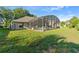 Screened-in pool area featuring a covered patio, lush landscaping, and plenty of space for entertaining at 1956 Southern Dunes Blvd, Haines City, FL 33844