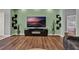 Cozy living room featuring wood floors, an entertainment center, and decorative plants at 25105 Laurel Valley Rd, Leesburg, FL 34748