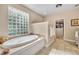 Bright bathroom featuring a soaking tub with glass block window and walk-in closet at 413 Harbour Oaks Pointe Dr, Edgewood, FL 32809