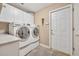 Well-lit laundry room featuring a modern washer and dryer, tiled floors, and ample storage space at 413 Harbour Oaks Pointe Dr, Edgewood, FL 32809