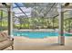 Inviting screened-in pool area with tile accents, surrounded by lush landscaping, and outdoor seating at 413 Harbour Oaks Pointe Dr, Edgewood, FL 32809