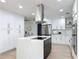 Open kitchen featuring stainless appliances, white cabinetry, large island, and hardwood floors at 4611 Cranston Pl, Orlando, FL 32812