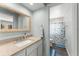 Bright bathroom featuring a granite vanity top, decorative mirror, and tile shower with a nautical themed curtain at 473 Burnt Tree Ln, Apopka, FL 32712
