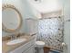 Bright bathroom featuring a granite vanity top, decorative mirror, and tile shower with a nautical themed curtain at 473 Burnt Tree Ln, Apopka, FL 32712