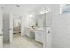 Well-lit bathroom with double sinks, white cabinets, and a glass-enclosed shower; bedroom view at 5314 Golden Apple Dr, Winter Garden, FL 34787