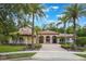 Stunning Mediterranean-style home featuring a red tile roof, arched entryways, and lush landscaping with palm trees at 5413 Via Veneto Ct, Sanford, FL 32771