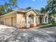 Exterior view of a home featuring a two-car garage, concrete driveway, arched entry and mature trees at 5489 Glen Oak Place, Sanford, FL 32771