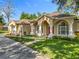 Charming home featuring an arched entryway, a red door, well-manicured lawn, and decorative landscaping at 5489 Glen Oak Place, Sanford, FL 32771