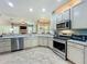 Kitchen featuring stainless steel appliances, light countertops, ample cabinetry, and views into the living room at 5489 Glen Oak Place, Sanford, FL 32771