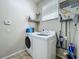 Well-equipped laundry room with modern washer and dryer, storage shelves, and tiled floor at 5489 Glen Oak Place, Sanford, FL 32771