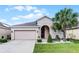 Charming one-story home featuring a two-car garage and a lush green lawn with tropical landscaping at 654 Star Magnolia Dr, Kissimmee, FL 34744