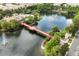 Aerial view of community pond, pool house, swimming pool, bridge and tropical landscaping at 661 Hangnest Ln, Lake Mary, FL 32746